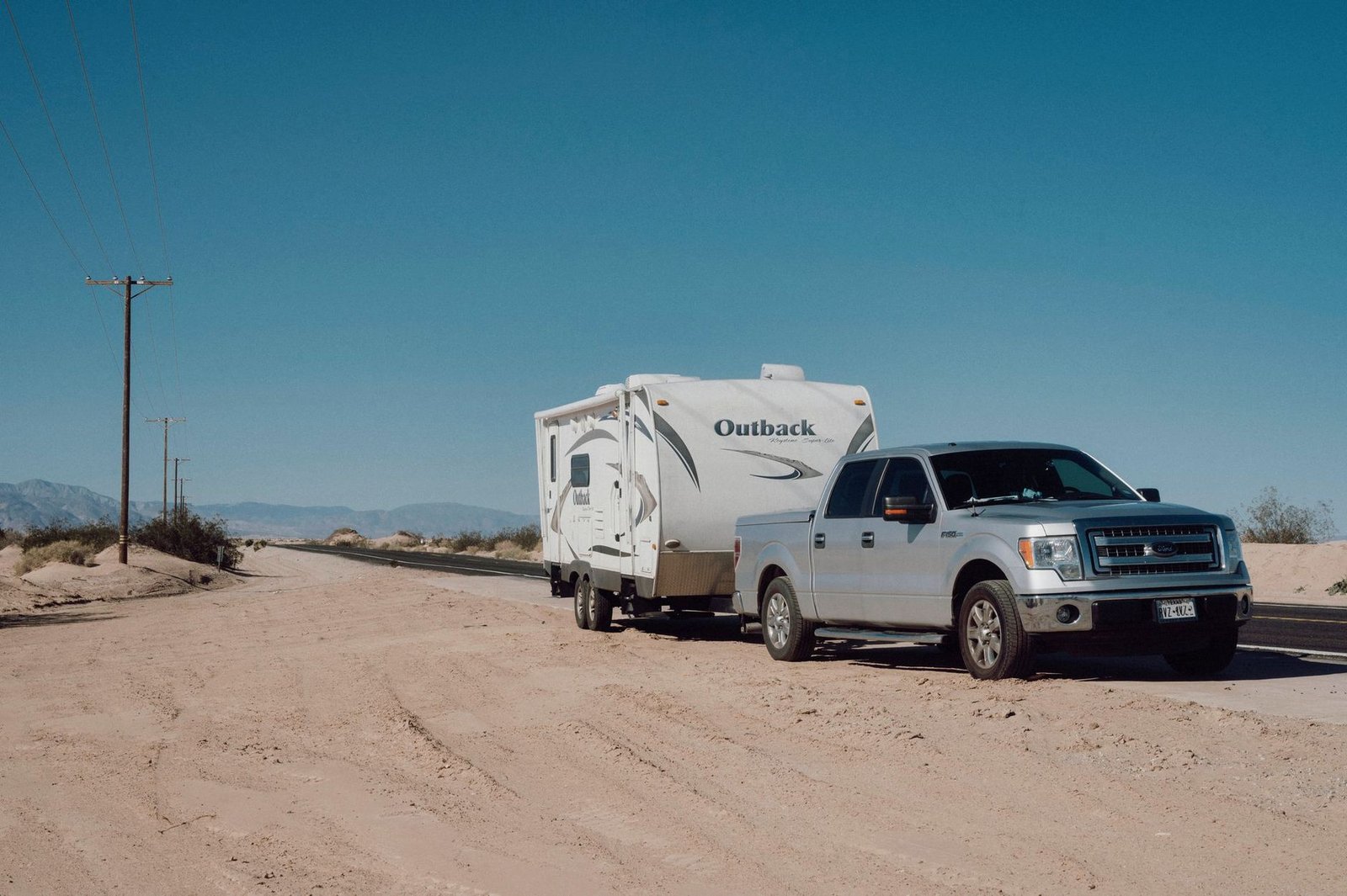 Ute towing a caravan along a desert road