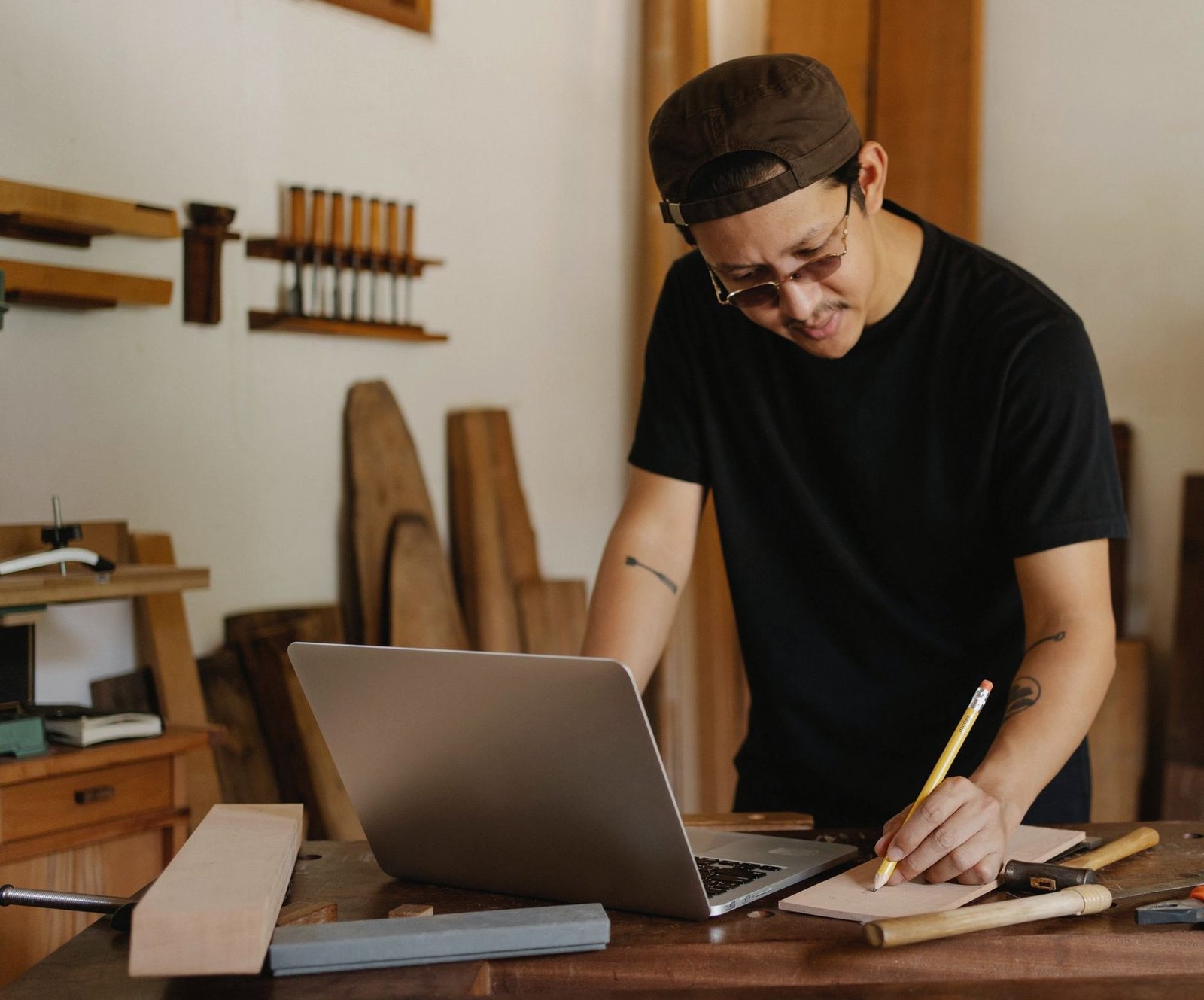 Tradie doing paperwork on a laptop in his workshop