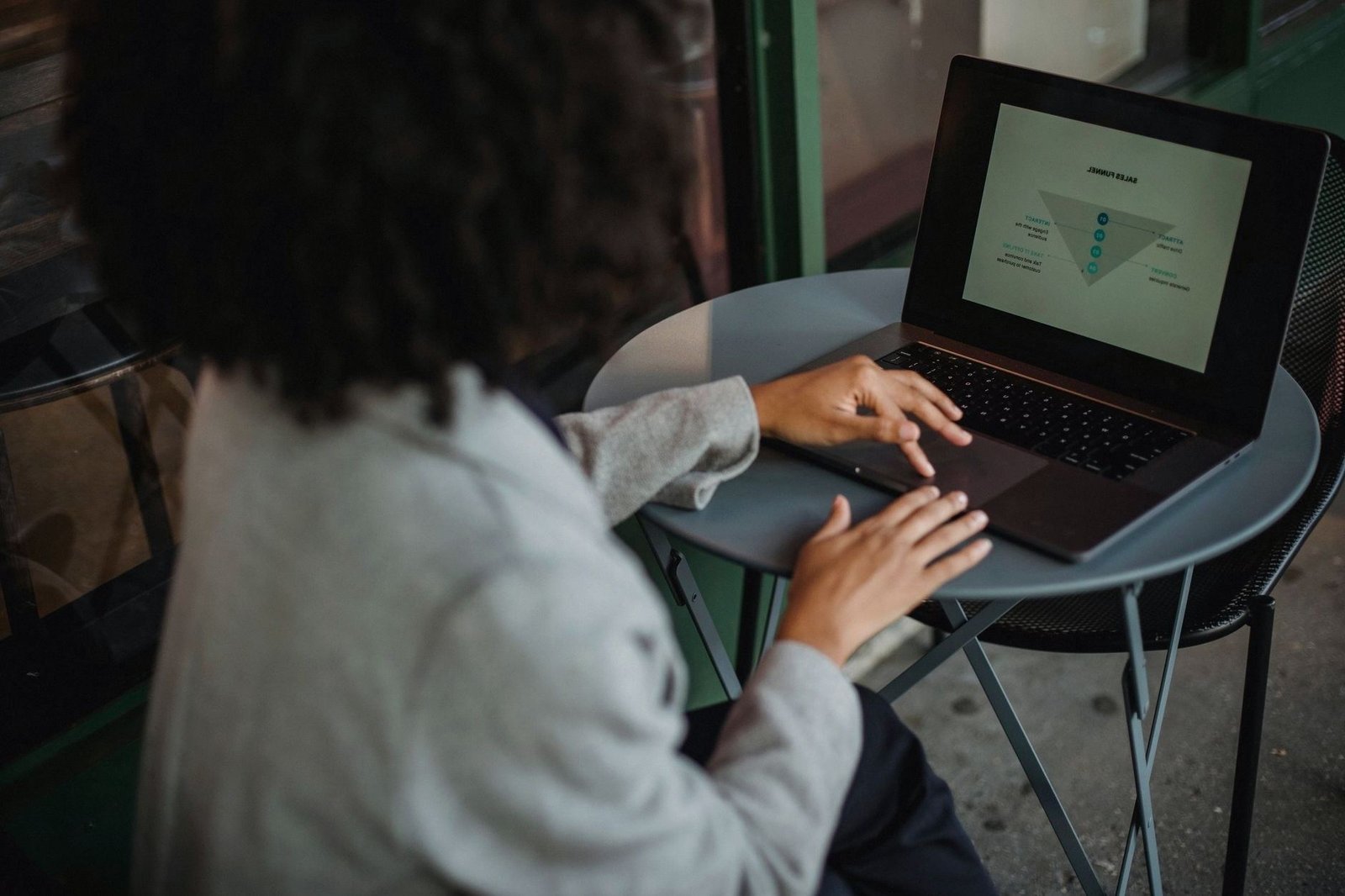 Woman working on a laptop at a cafe table