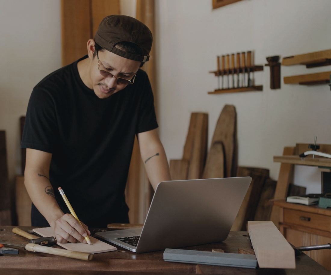 Self-employed tradie doing paperwork on a laptop in his workshop